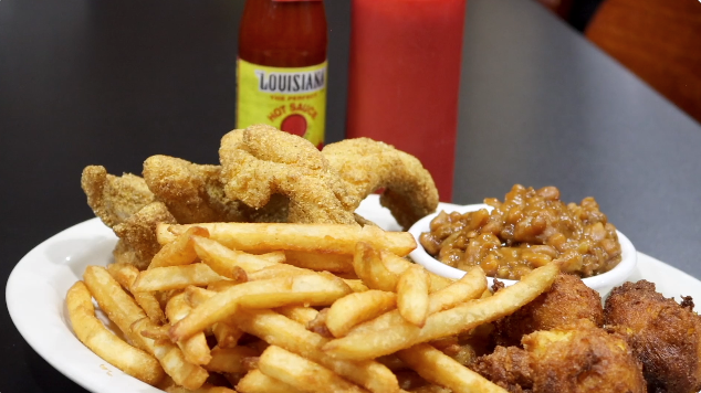 Plate of fried catfish fries, beans and hush puppies